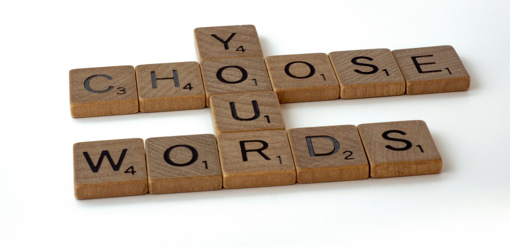 Scrabble tiles spelling out the phrase "Choose Your Words"
