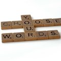 Scrabble tiles spelling out the phrase "Choose Your Words"