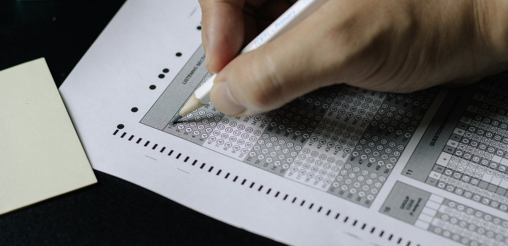Close up of a person filling out an SAT answer sheet with a pencil
